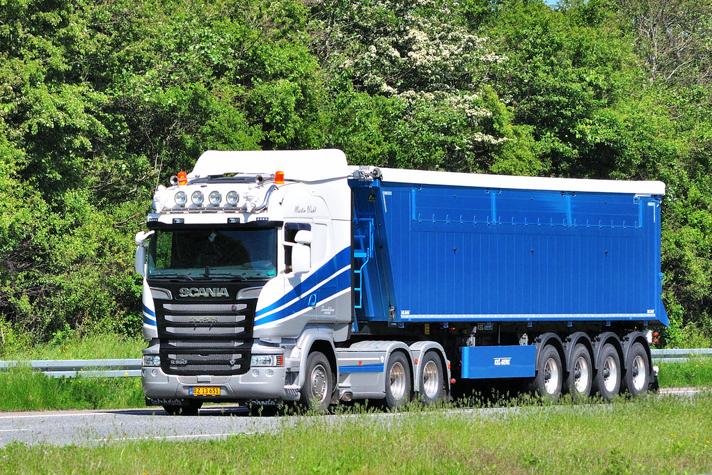 Articulated lorry travelling along a tree-lined road